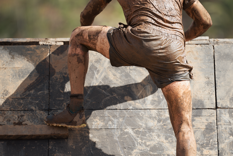 obstacle-race-runner-climbing-in-mud